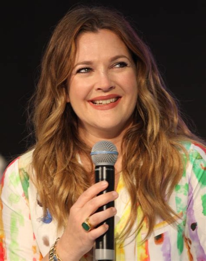 Actor Drew Barrymore clutches her birthday hat and smiles for paparazzi on her birthday