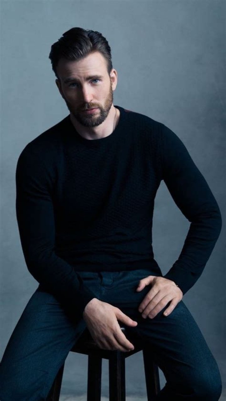 Chris Evans posing in a white shirt and grey jeans during a Marvel event.