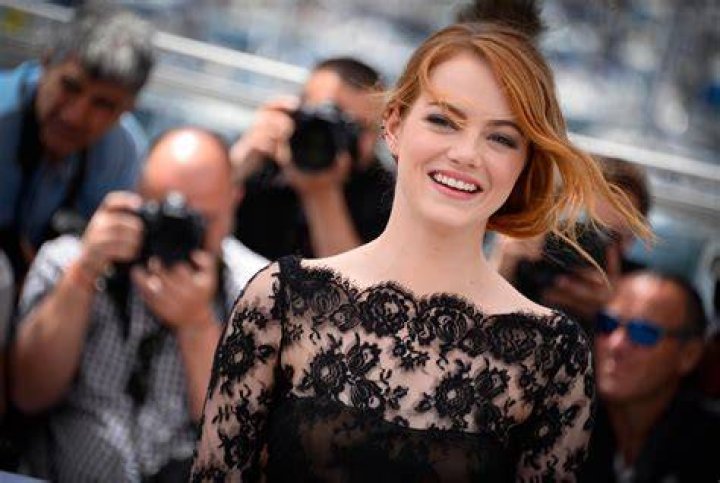 Emma Stone smiling while wearing a blue dress.
