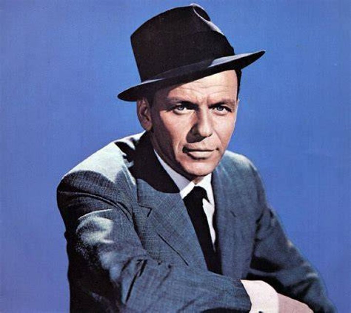 Frank Sinatra wears a hat and a red tie.
