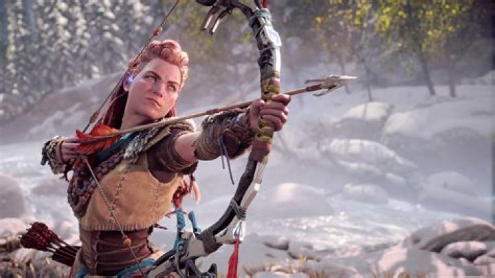 Horizon Forbidden West. Aloy is facing a large and angry Tremortusk machine on a beach.