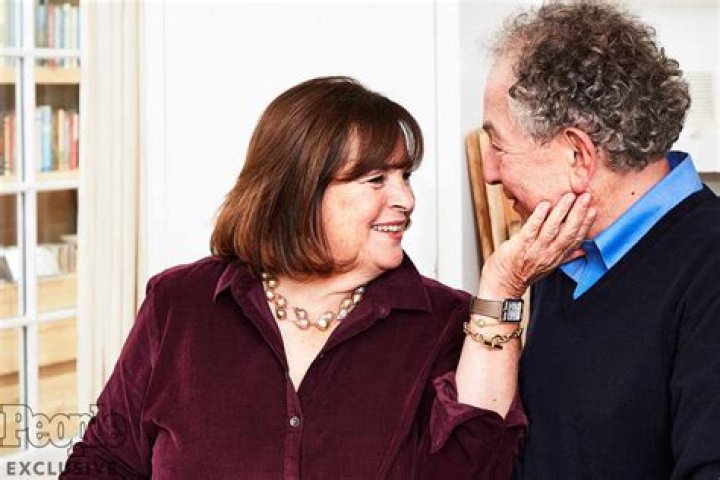 Ina Garten wears a bright blue shirt and cooks with Stephen Colbert who is seen drizzling oil