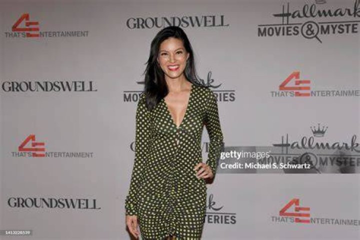 Isabelle Du from the Hallmark movie 'Hidden Gems' sitting on a surfboard
