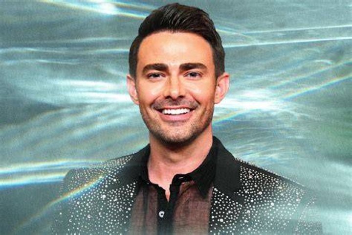 Jonathan Bennett smiles for the camera wearing a blue jacket.