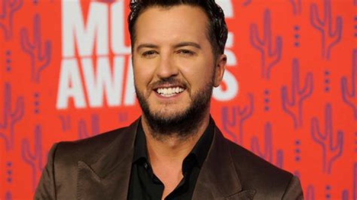 Luke Bryan smiling big while sitting next to his wife, Caroline Bryan, at the CMT Music Awards