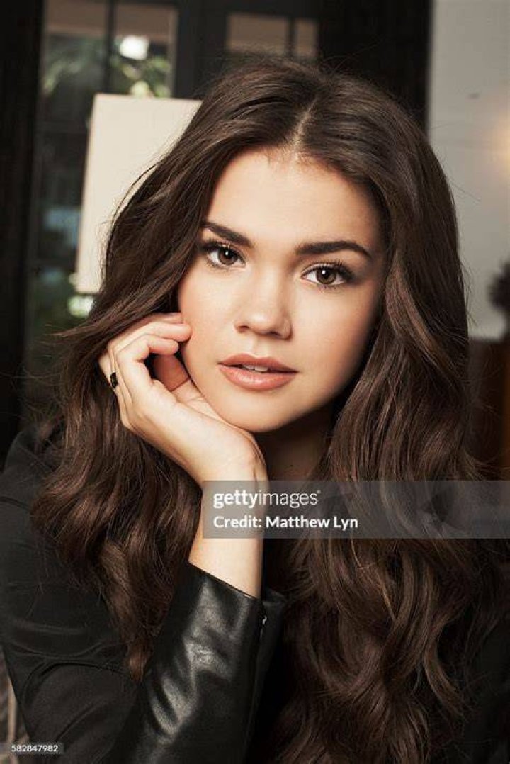 Maia Mitchell smiles while wearing a black dress on 'Good Trouble.'