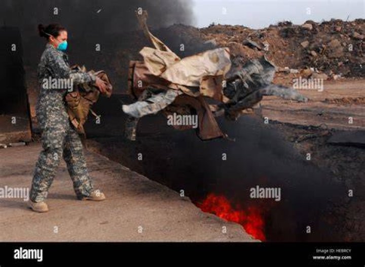 Senior Airman Frances Gavalis tosses unserviceable uniform items into a burn pit March 10 at Balad Air Base, Iraq. Military uniform items must be burned to ensure they cannot be used by opposing forces, according to the U.S. military. Photo by U.S. Air Force/Senior Airman Julianne Showalter