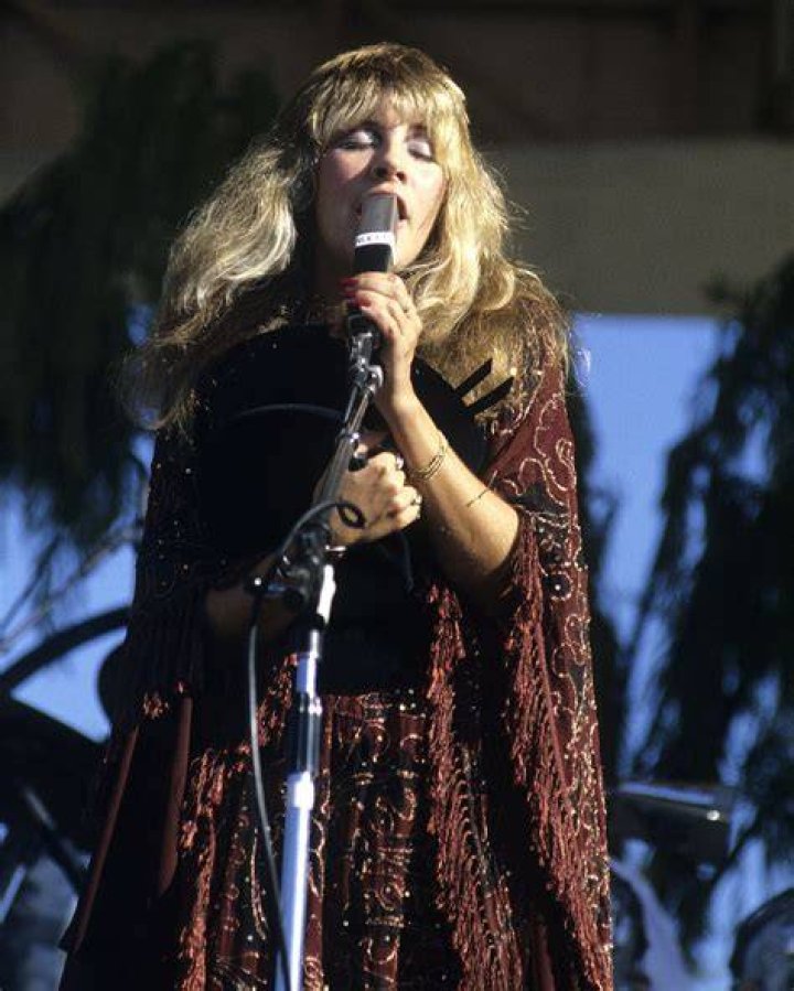 Stevie Nicks stands on stage in a black outfit